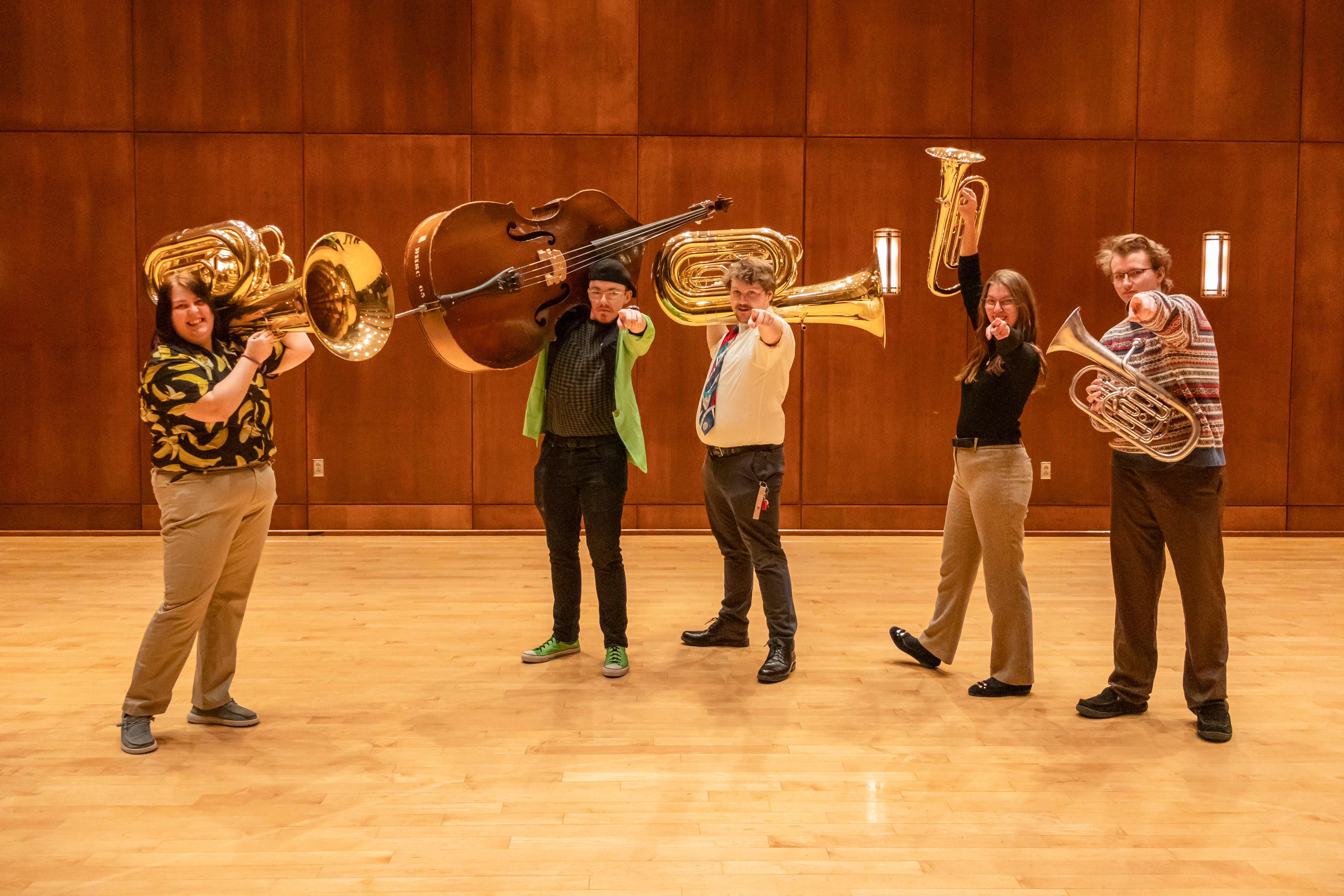 Five BHSU band students pose for a photo, holding their instruments and pointing at the camera.
