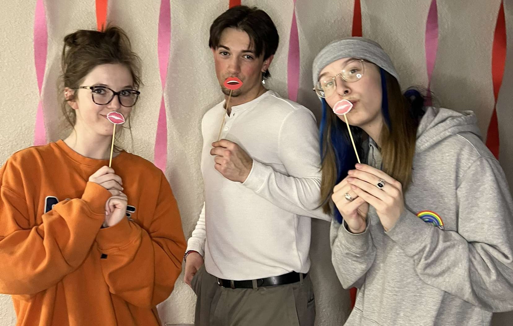Three BHSU students holding up valentines lips on sticks to their mouths to pose for a photo at an All-Hall event in the residence halls.